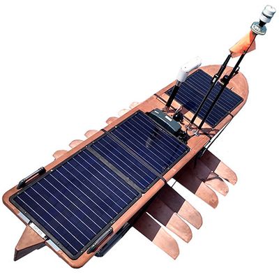A long board covered with dark blue solar panels with copper colored fins below and a mast sticking out from the top.