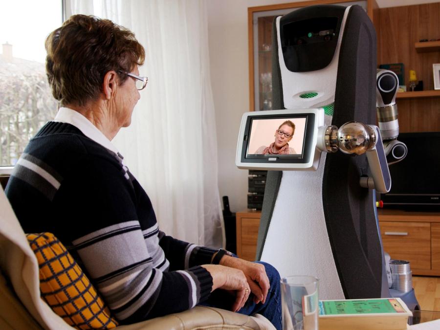 A display on the robots arm shows a video call to an elderly woman.