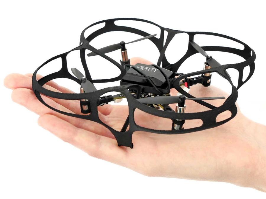 A small black drone in a simple cage in the palm of a hand.