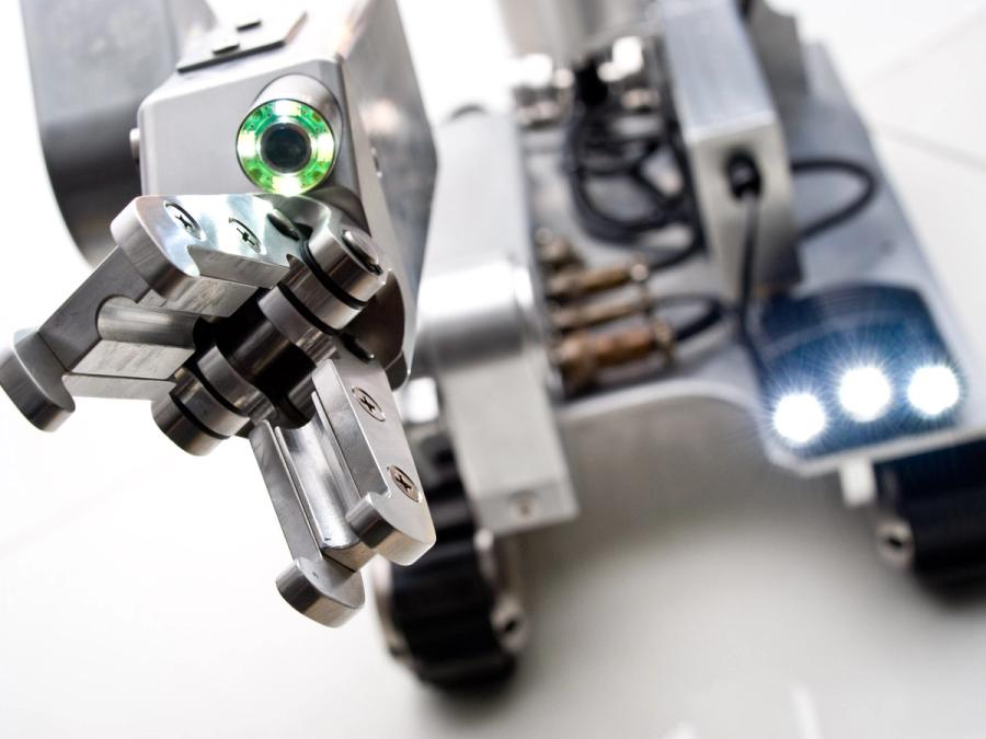 Close-up of the robots open gripper hand. A glowing camera is in wrist.