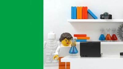 A Lego minifigure customized as a female scientist holds a beaker in a Lego lab that features a skeleton, gears, and a computer.