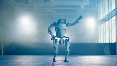 Humanoid robot HD Atlas stands on a foggy lab space while lifting one arm.
