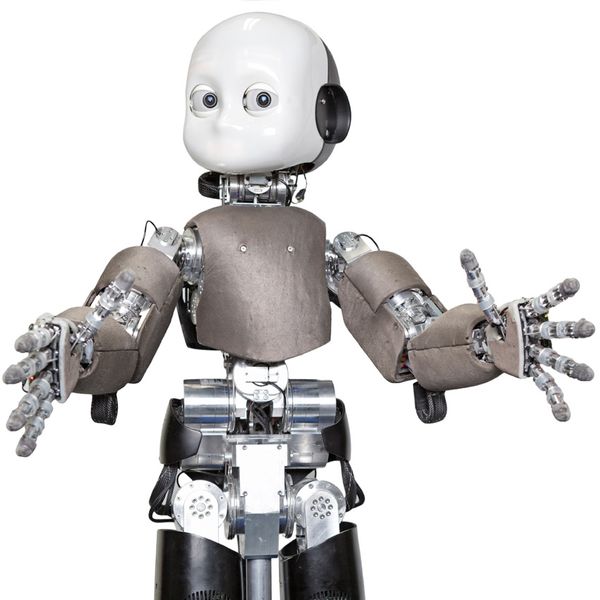 Child robot iCub, with a white face with round eyes, gray torso, and extended arms as if offering a hug, set against a white background.
