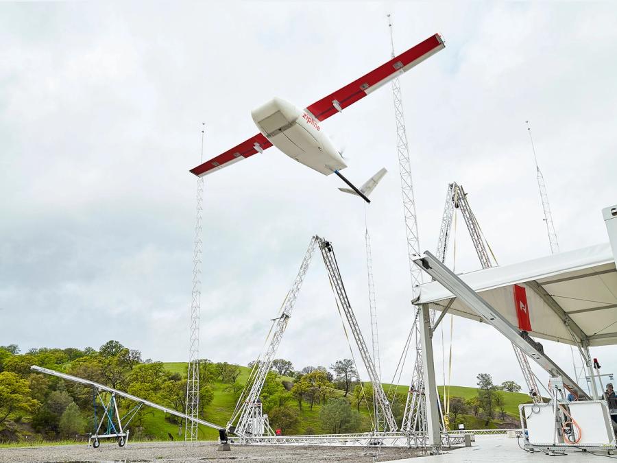A large red and white fixed-wing aircraft drone takes off from a silver platform.