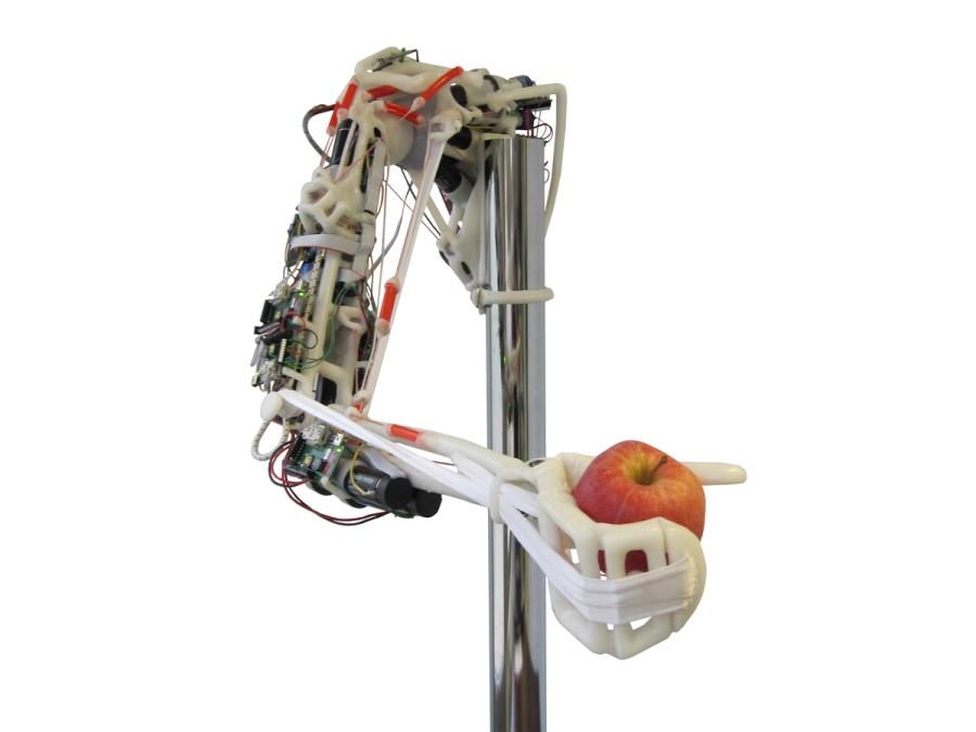 The robots arm is on a frame, and its hand holds an apple.