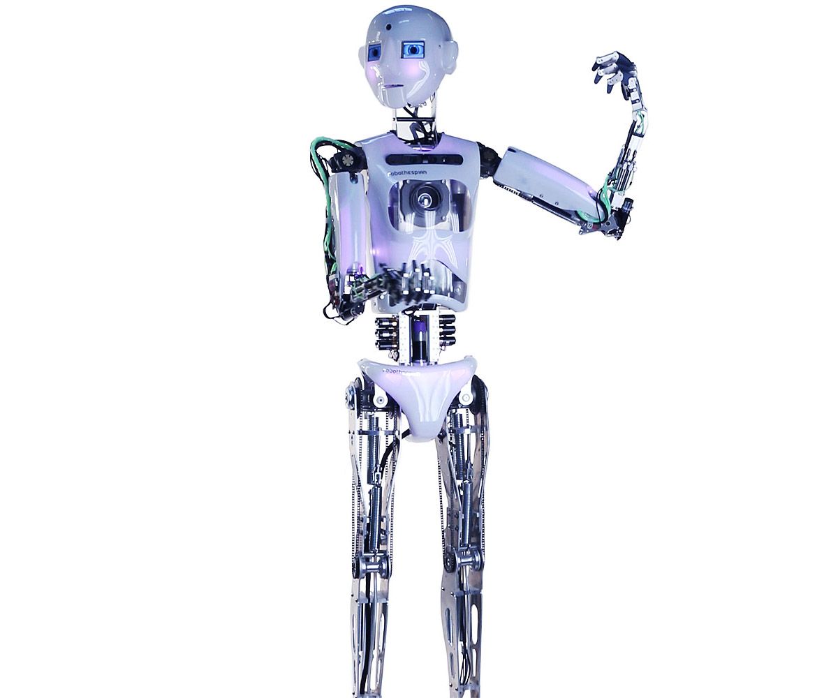 A spinning view of an expressive legged humanoid robot with a bright round face, a shiny torso with sensors, and two arms with black jointed fingers.