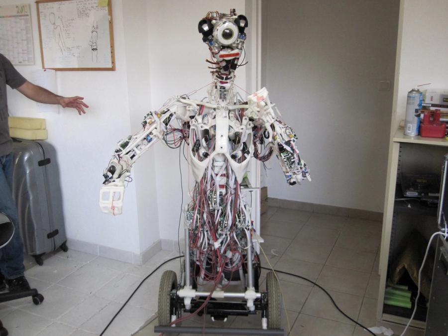 A one-eyed, wheeled humanoid robot whose wire-filled insides are exposed.