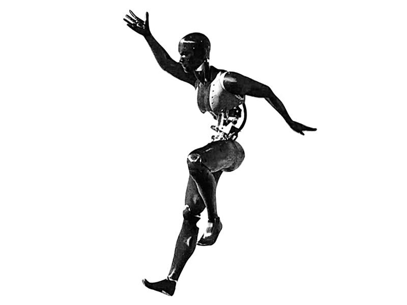 A black humanoid in an active position as if catching itself while falling. It's arms are thrown out to the side, one leg is bent up and the other foot has only the heel on the ground.