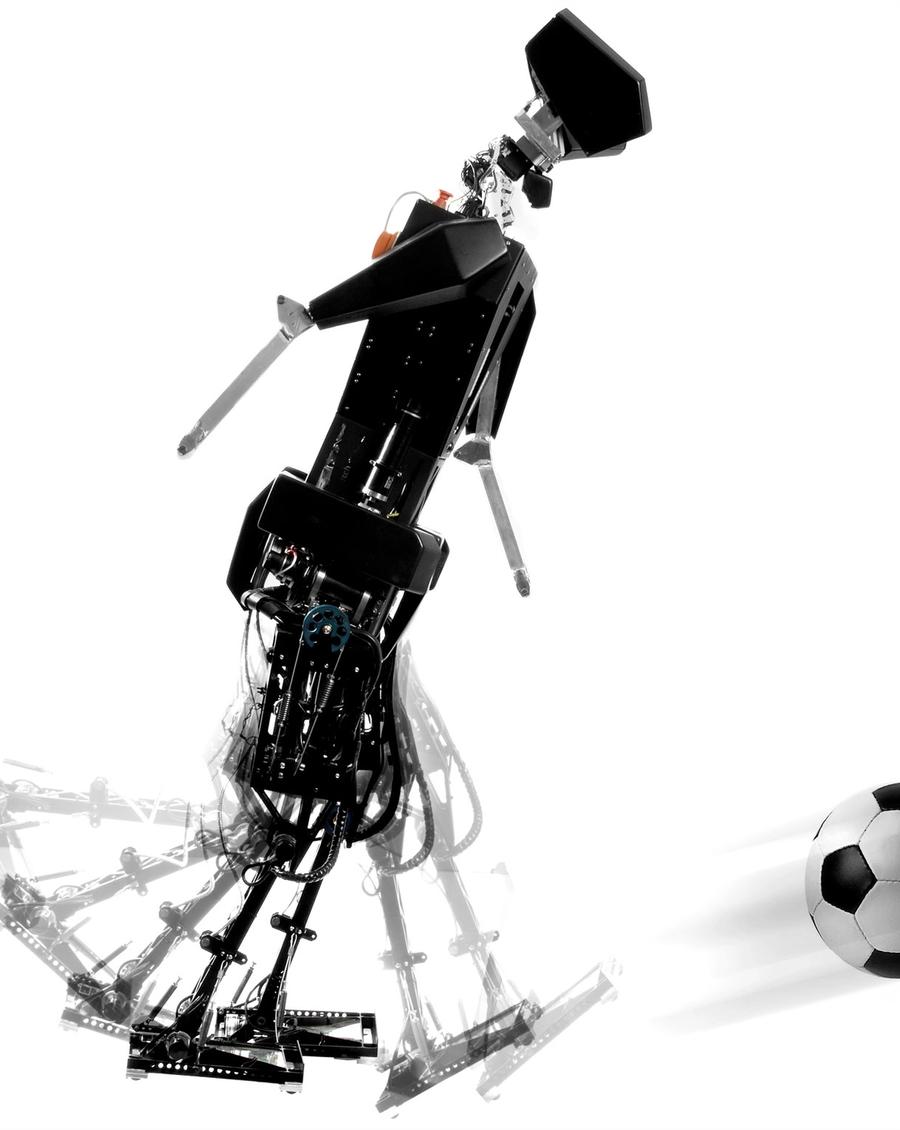 A bipedal robot is seen in a multiple exposure image kicking a soccer ball.