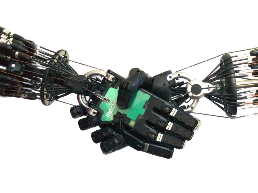 Two black prosthetic hands that imitate human fingers and tendons shake hands.