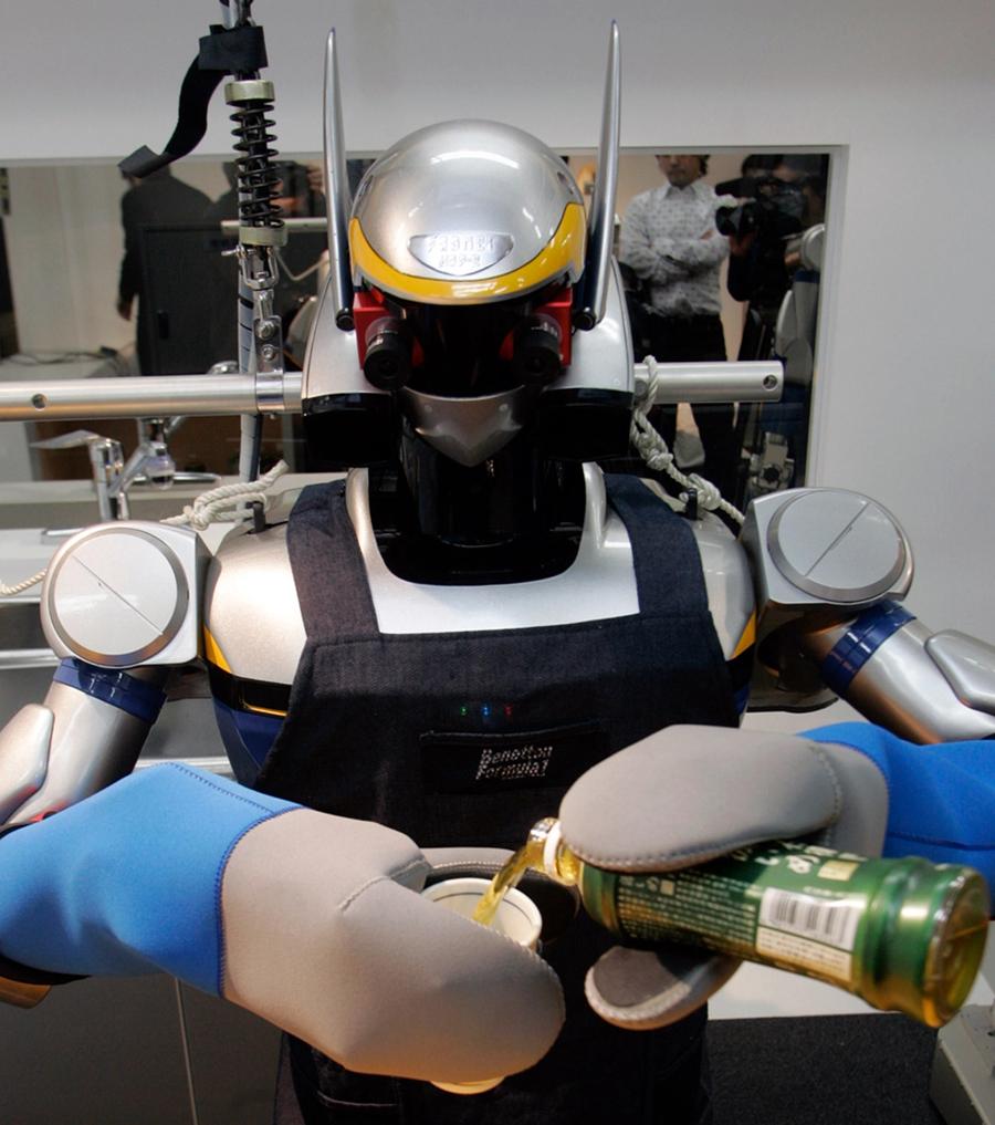 Close-up of the robot wearing an apron and oven mitts as it pours from a bottle into a cup.