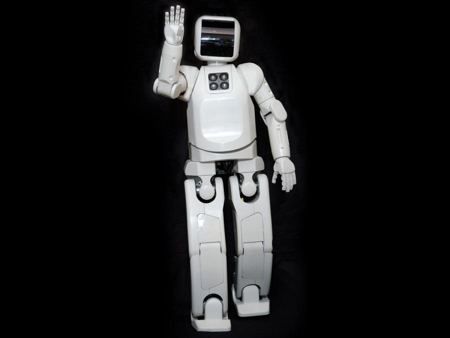 A white robot with a black face plate waves at the camera