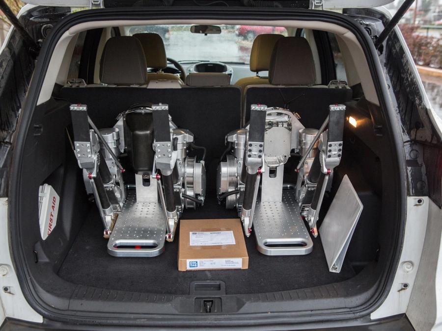 The robot in pieces in the trunk of a car.