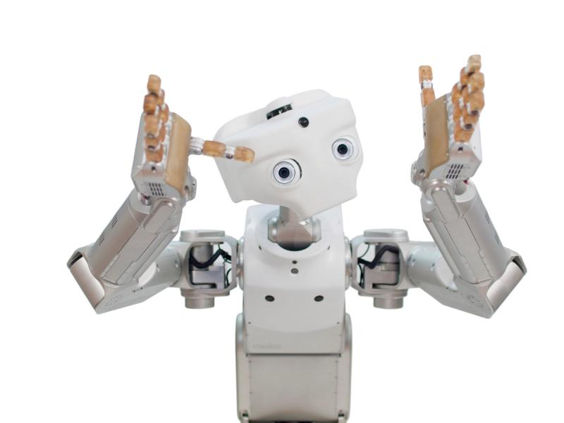 A white robot with a simple face with two eyes and a camera. It has two hands with five gripper fingers which it holds up as if gesturing.