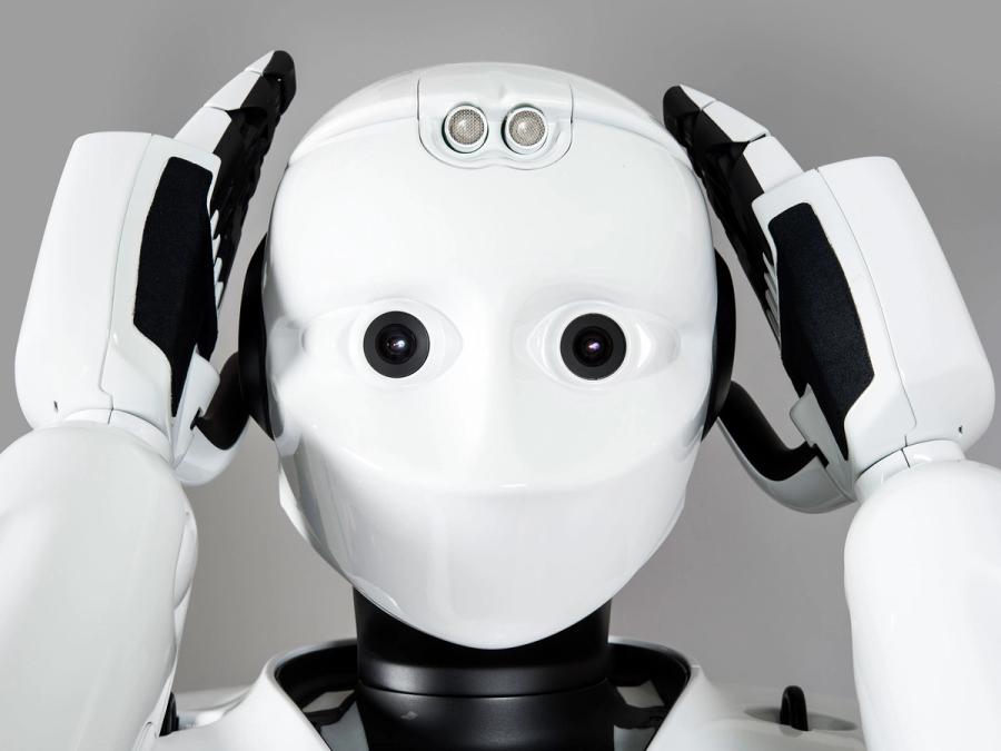 Close up of the robots face showing multiple sensors. It's hands are resting on either side of its face.