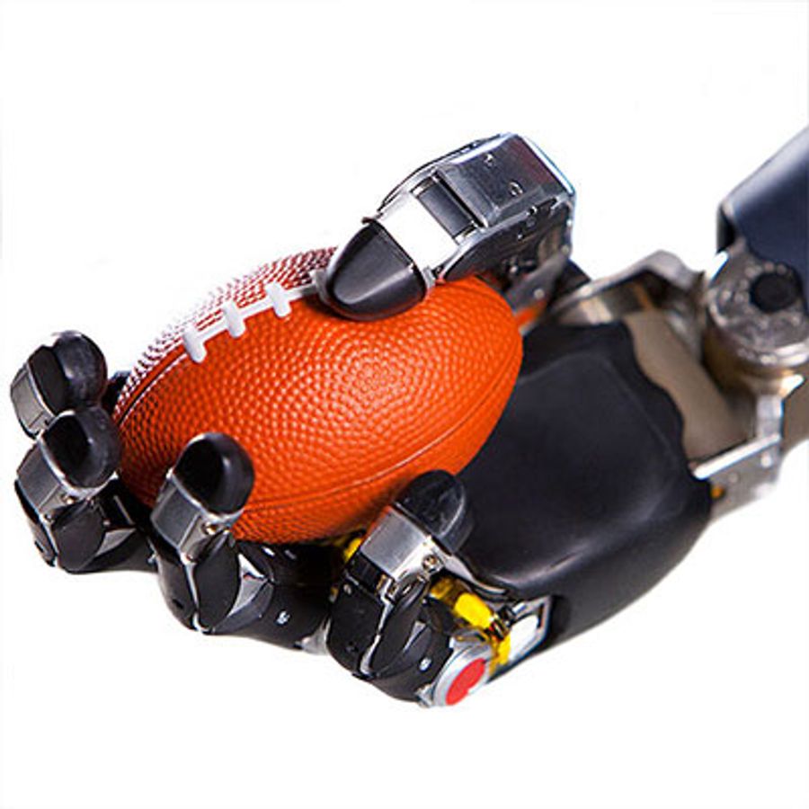A bionic hand squeezes a miniature football.