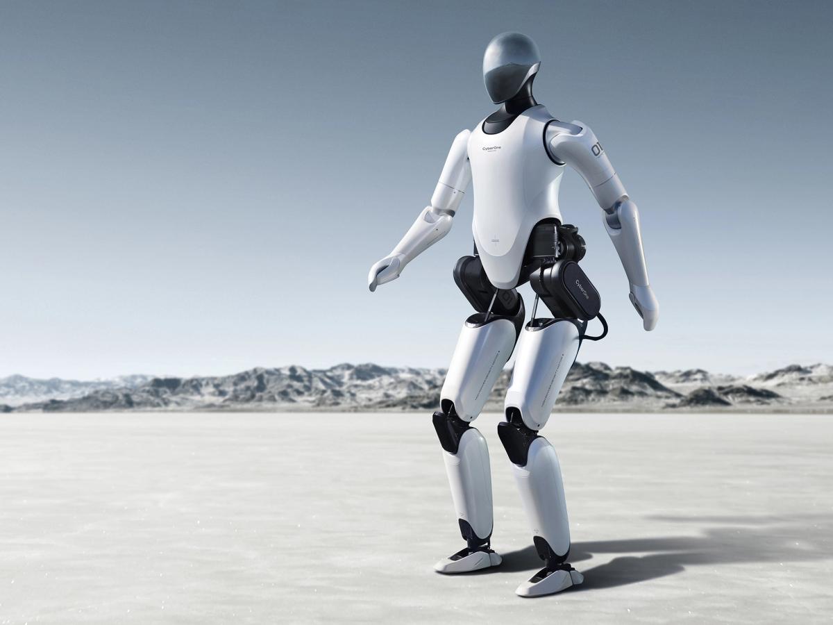 Xiaomi's CyberOne is a white and black bipedal humanoid with a helmeted head poses in a balanced position. It is pictured as being in a desert environment.