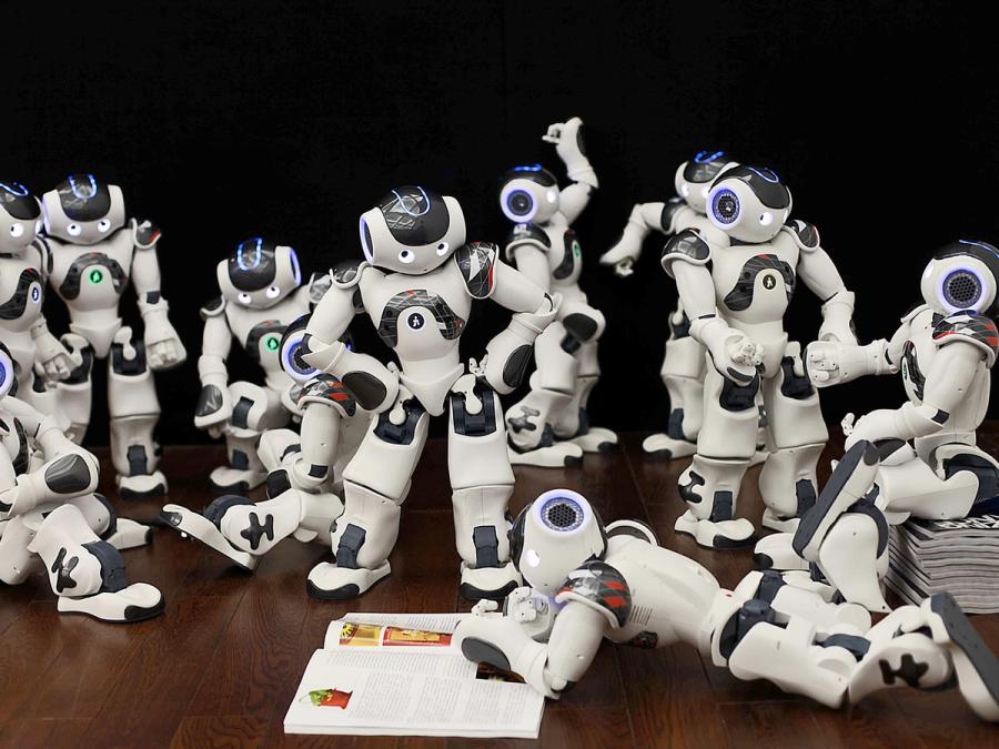 Ten Nao robots are posed as if chatting and interacting with each other.