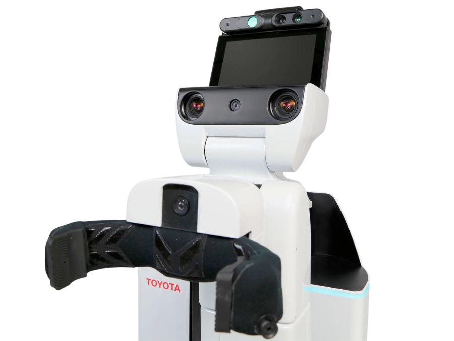 A black and white robot with a black claw-like gripper on its torso, and a head composed of camera eyes and a tablet display.