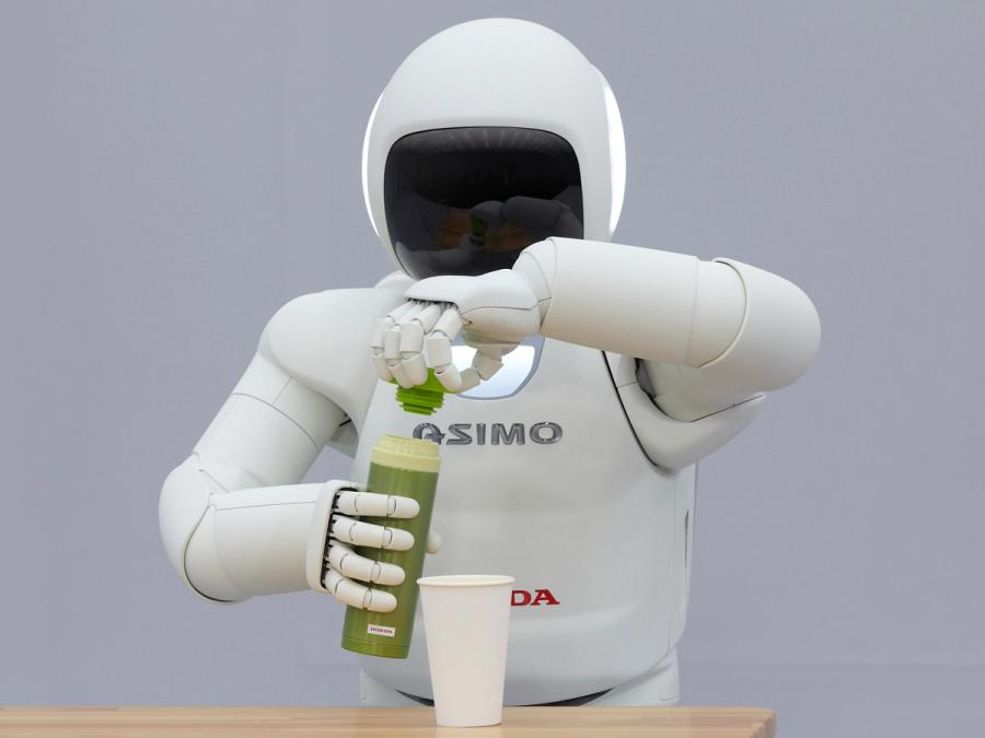 Honda's Asimo robot opens a bottle full of a green liquid in front of a cup.