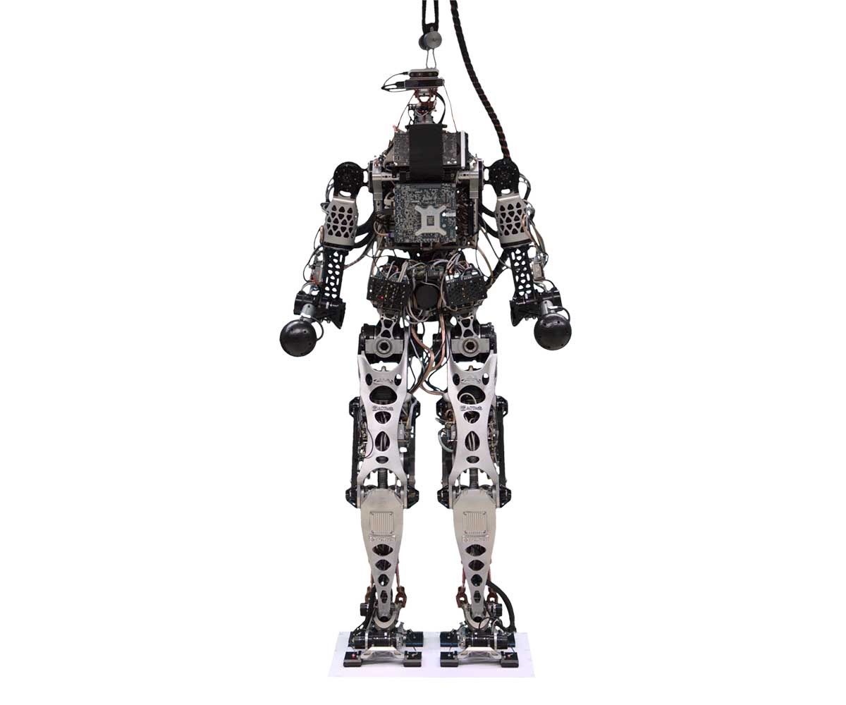 A spinning view of a humanoid bipedal robot with exposed electronics and a head consisting of two stacked rectangles with cameras and sensors.