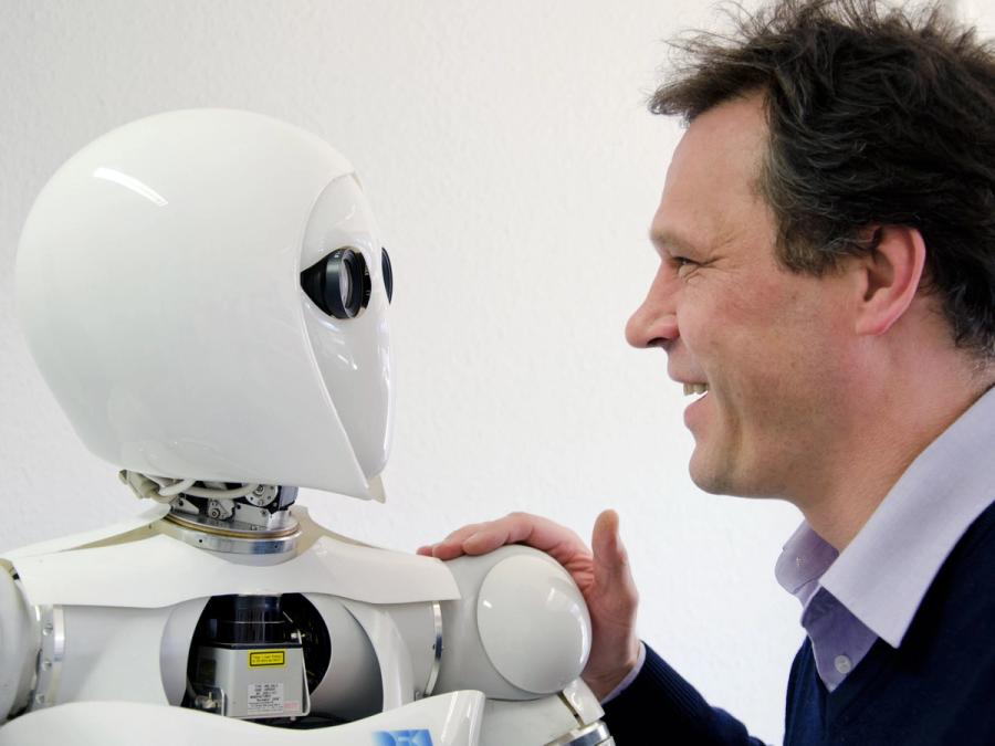 A man and a robot look each other in the eye.
