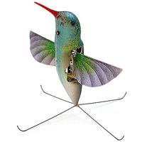 A robot that looks like a hummingbird including wings and long, thin, orange bill stands on a four pronged base.