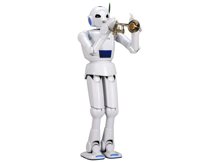 Full body view of the simple white humanoid robot as it plays a trumpet.