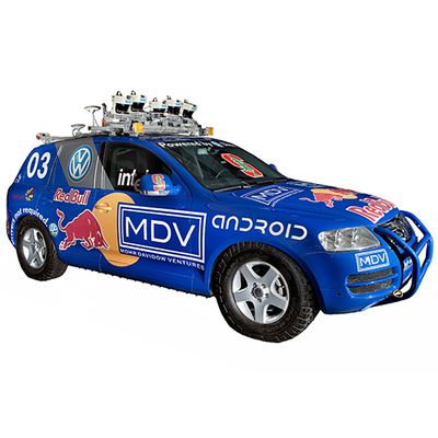 A blue, logo covered self-driving car with a roof rack full of electronics.