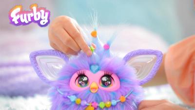 A purple Furby decorated with beads by a child's hand.