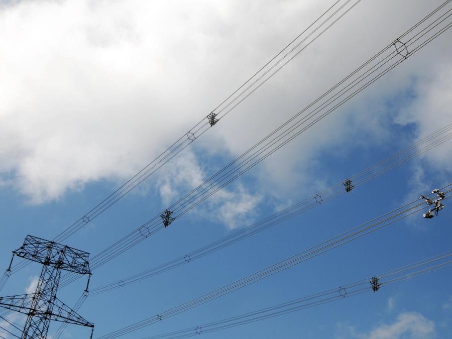 Photo of an electricity pylon and many high-voltage lines. The robot is seen from a distance on the cables.