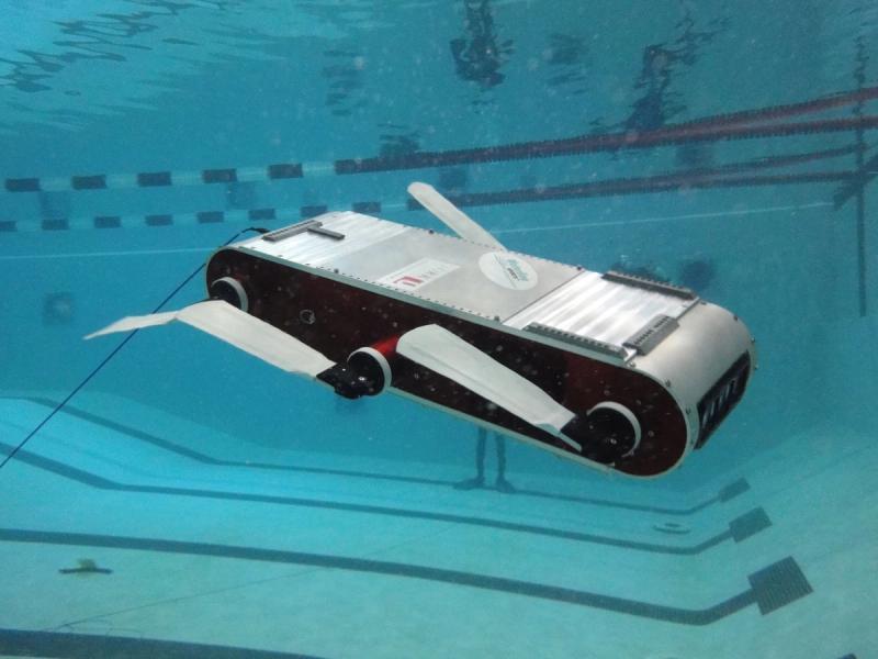 A rectangular gray and black robot with gray fins underwater.