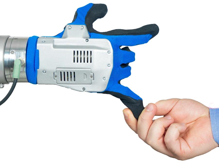A human hand pulls on one of the robotic hands fingers.
