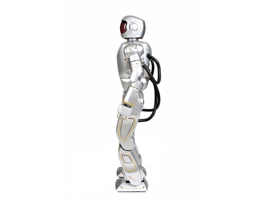 Side view of a sleek silver humanoid with a helmeted head, and thick black wires on its back.