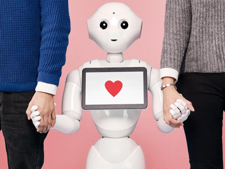 A friendly white robot with a heart displayed on its tablet holds hands with two larger adult humans.