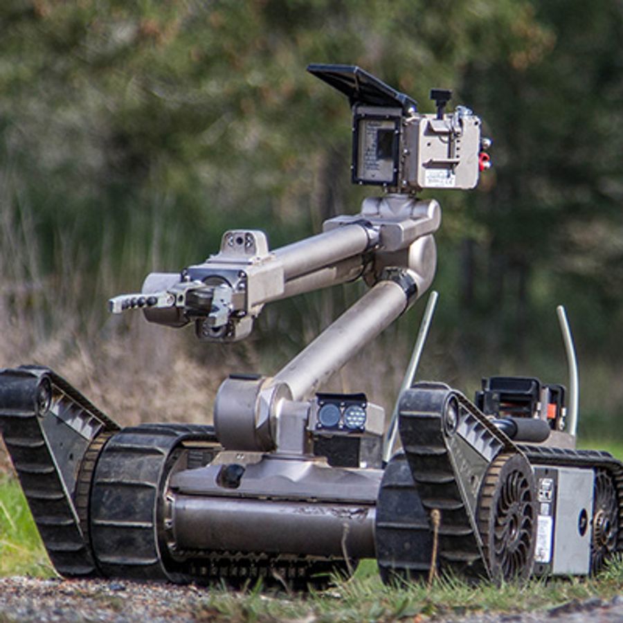 A single armed robot on treaded wheels.