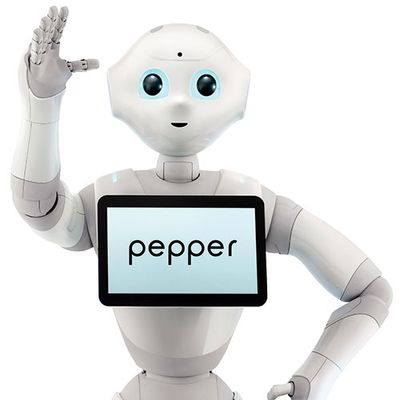 A friendly white humanoid with a simple face with glowing blue lights around its eyes waves at the camera. It has a tablet on its chest which says pepper.