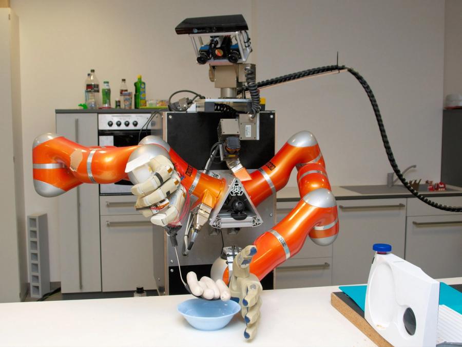 A robot with two advanced industrial arms uses kitchen tools to place four sausages into a bowl.