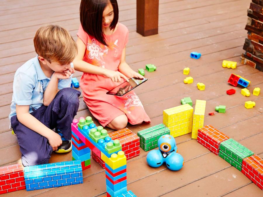 Two children play with a blue robot that looks like three balls pushed together.