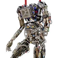 A complex humanoid bipedal robot is shown with its wires, actuators and sensors exposed.