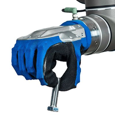 A robotic hand attached to a cobot arm pinches a bolt between two fingers. The hand has metal on top, and is covered in blue and black soft material.