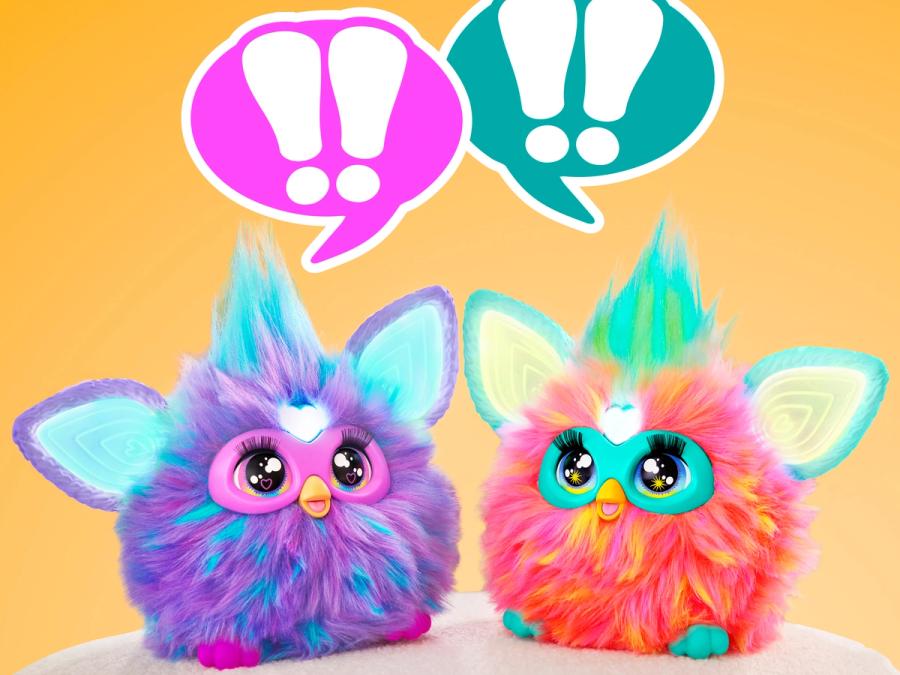 Two Furby robots, squat hairy toys that are a cross between a bird and an owl, each with a tuft of hair sticking straight up, and glowing ears.