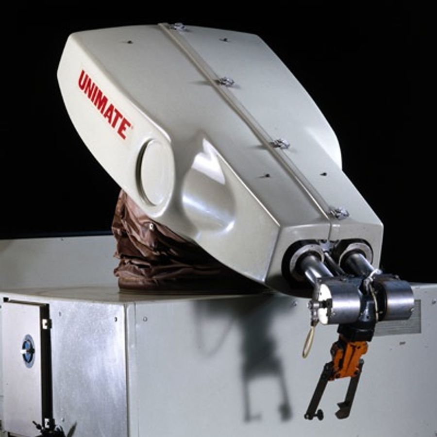 A historical factory robot labelled Unimate has a boxy base, white arm and gripper end piece.