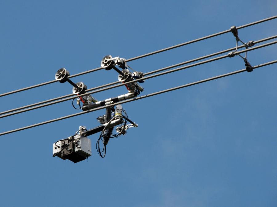 An industrial robot with an articulated arm laden with equipment on a high-voltage power line.