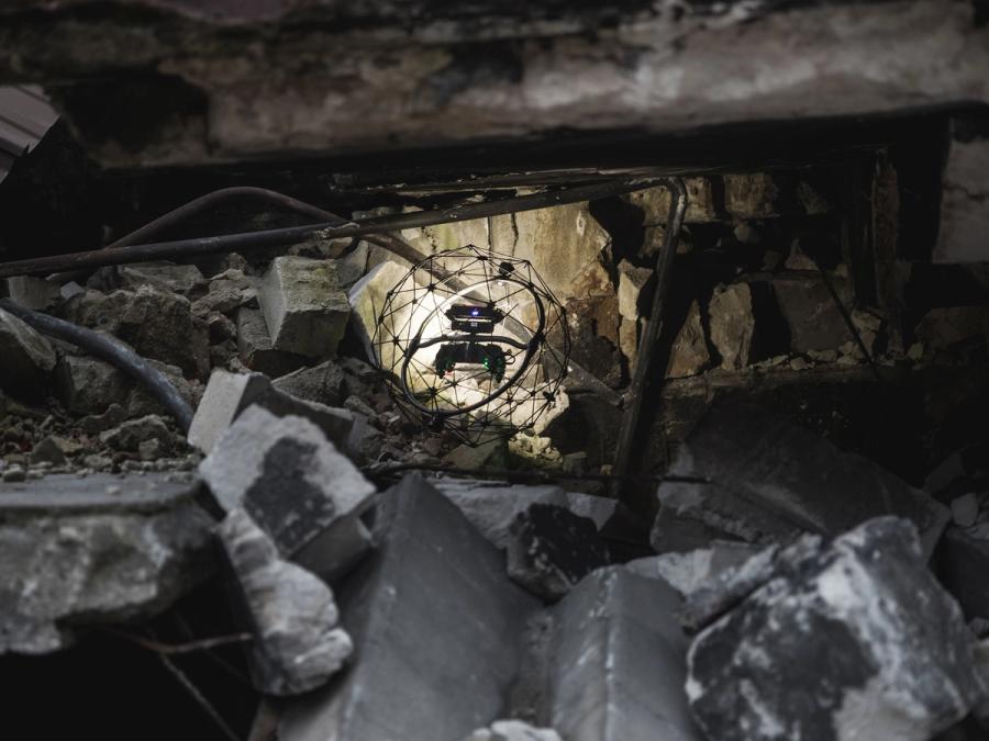 The drone in its protective cage flies in tight space full of rubble.
