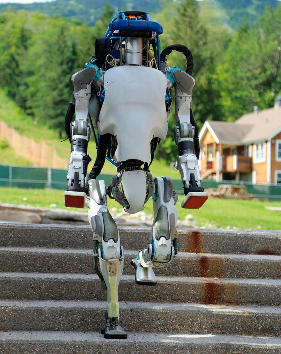 A humanoid robot goes down a set of outdoor stairs.