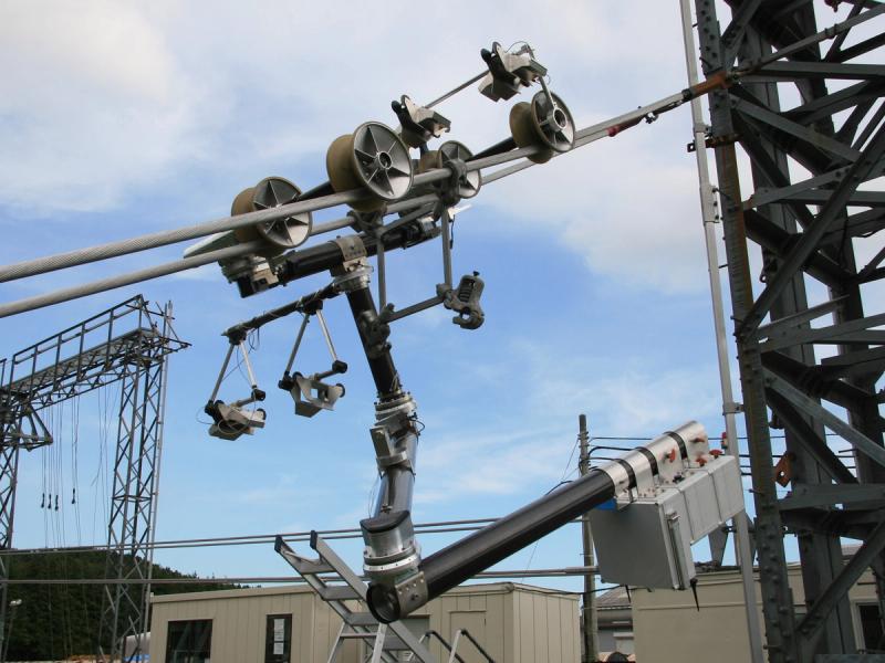 An industrial robot with an articulated arm uses specialized wheels to move along a high-voltage power line.
