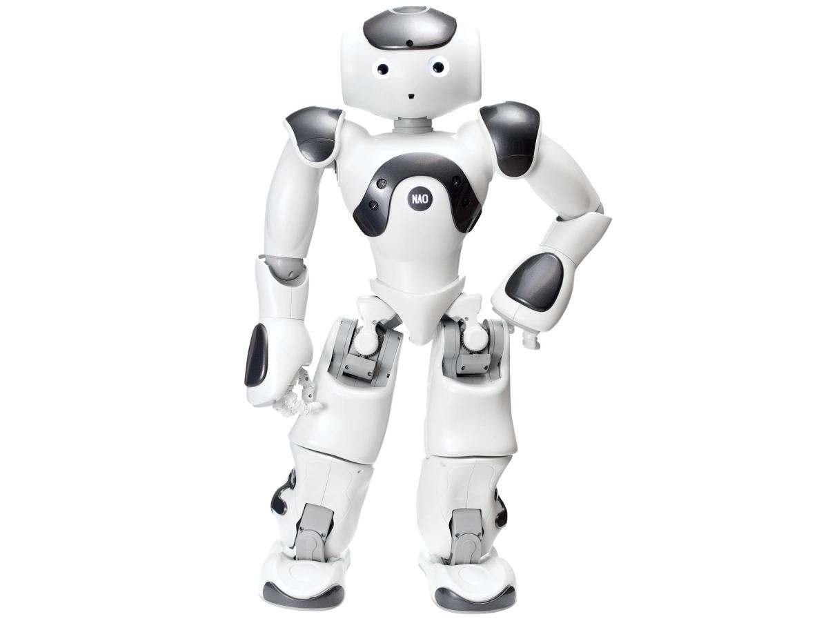 Nao, a friendly, cartoonish, white and silver humanoid robot stands with one hand on it's hip. It has two eyes and a small hole with forms its mouth.