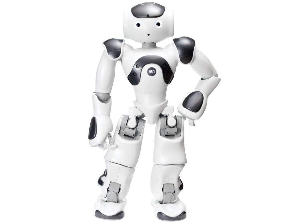 A friendly, cartoonish, white and silver humanoid robot stands with one hand on it's hip. It has two eyes and a small hole with forms its mouth.