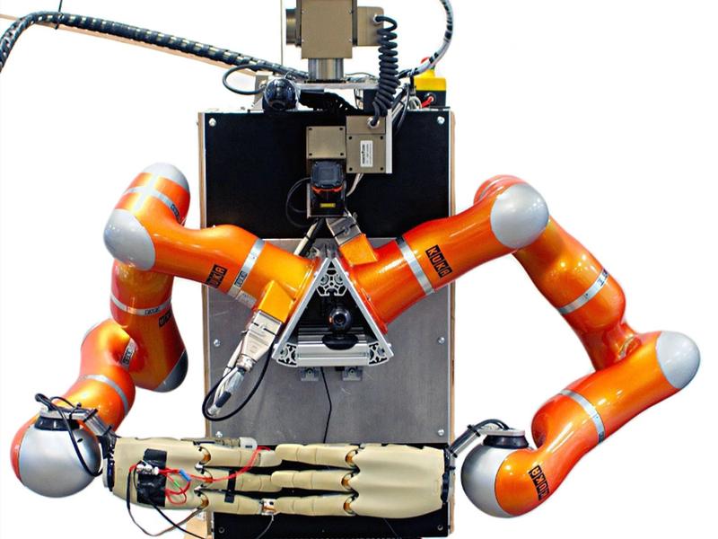 A vertical rectangular box on wheels supports two industrial orange arms and hands with four fingers. The robots head is composed of cameras and a sensor bar.